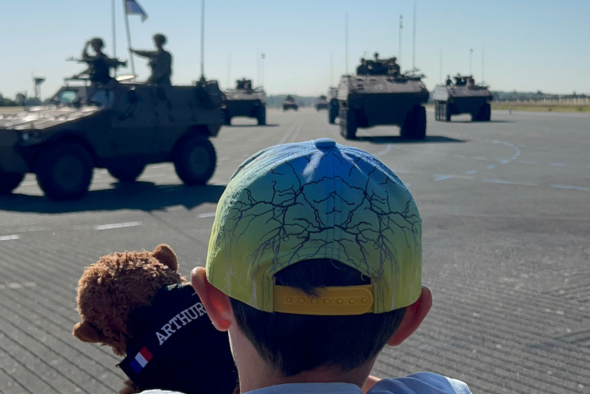 Orphelins d'Orphéopolis observant les chars militaires défilés