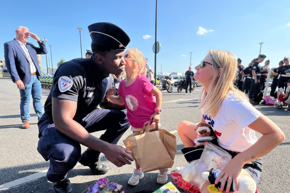 Orpheline d'Orphéopolis avec sa maman, faisant un bisous à un policier après avoir ouvert ses cadeaux.