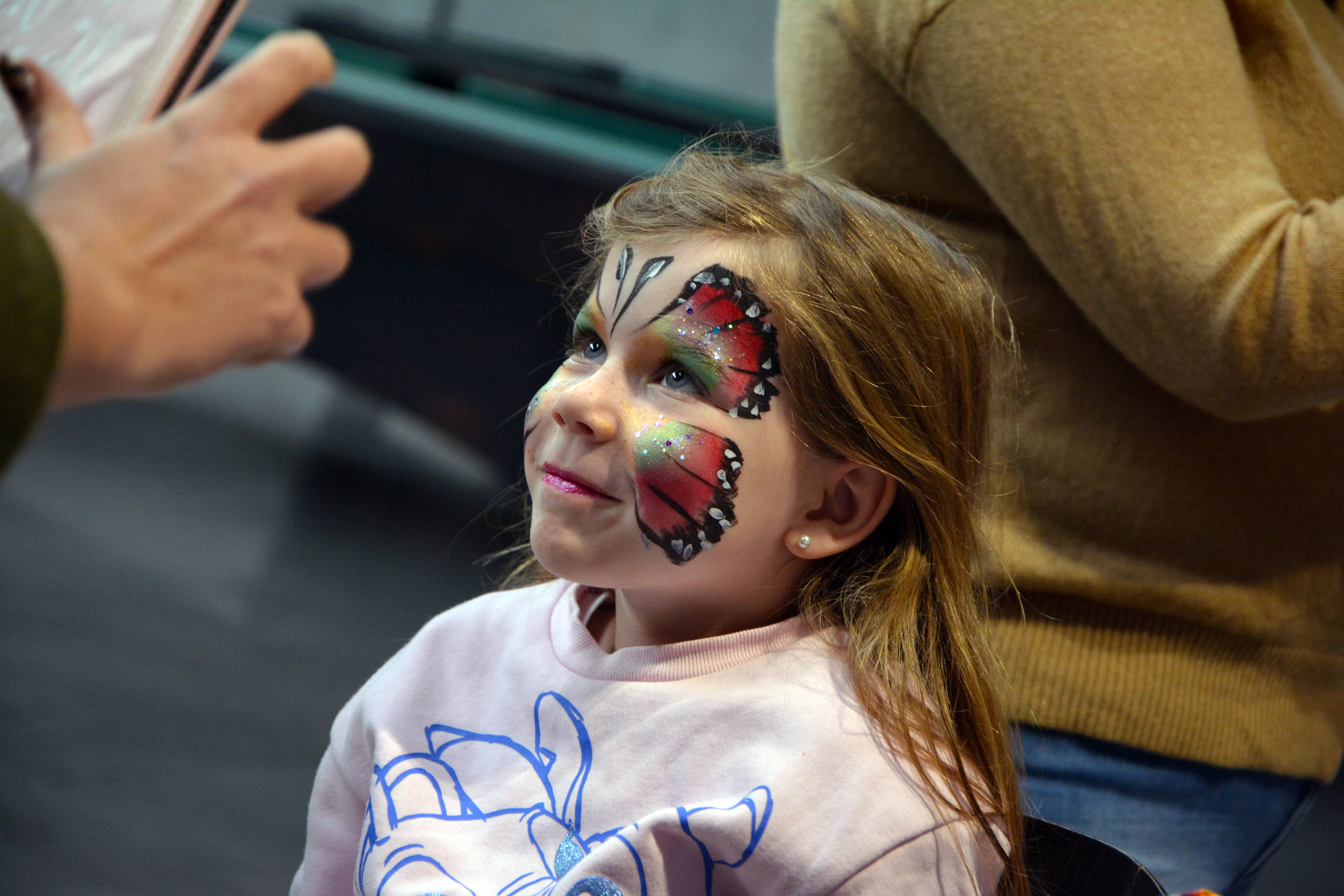 petite fille maquiller au visage avec un dessin de papillon