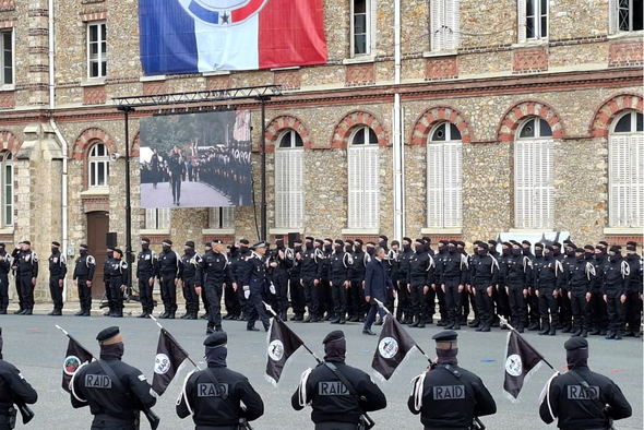 Les agents du RAID au garde à vous devant leurs emblèmes
