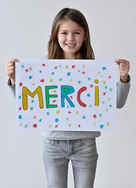 Fillette tenant un panneau Merci