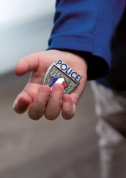 Enfant tenant un écusson police dans le creux de la main
