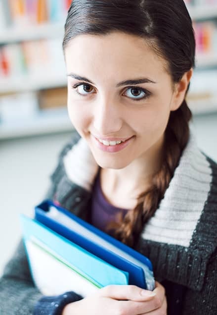 Jeune fille qui tient des cahiers dans les bras